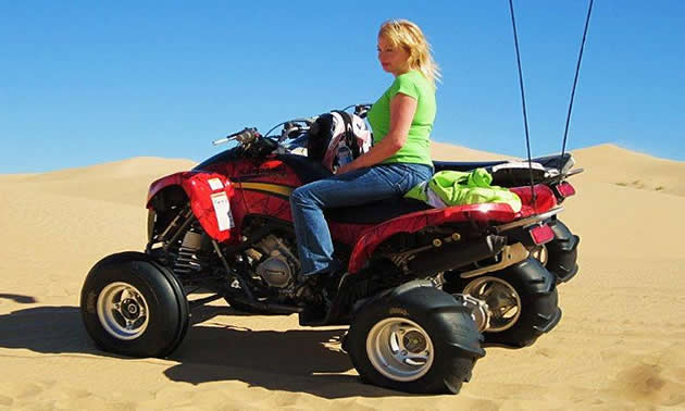 A woman on a quad in the desert.