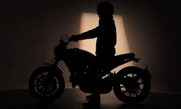 A person on a motorcycle in shadows. 