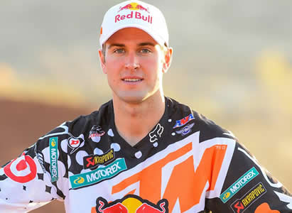 Ryan Dungey standing beside his KTM wearing a white Red Bull cap. 