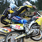 Photo of two guys battling it out on in a dirt bike race.