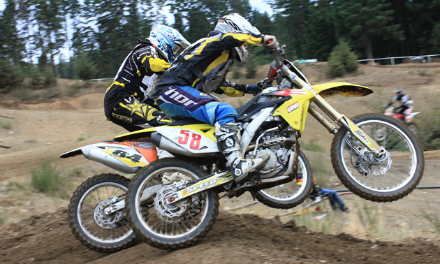 Photo of two guys battling it out on in a dirt bike race.