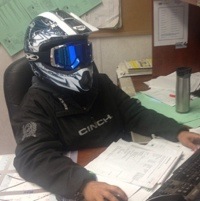 Erin Wairachowski sitting at her desk at work with a helmet on.