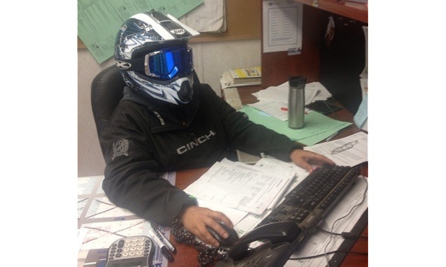 Erin Wairachowski sitting at her desk at work with a helmet on.