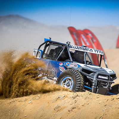 A Hellenbach Racing UTV is racing through desert sand.