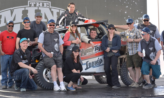 The team is posed next to one of its UTVs at the Mint 400.