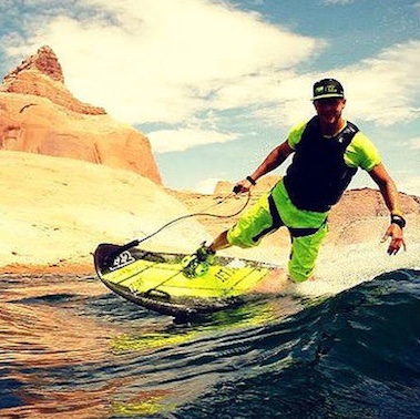 A man riding a JetSurf on a lake that is in the desert. 