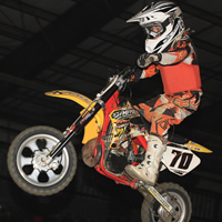 A young boy on a mini bike flying through the air. 