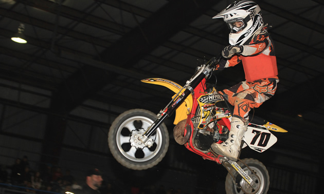 A young boy on a mini bike flying through the air. 