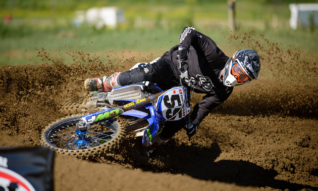 Professional motocross racer Keylan Meston leans hard into a corner on a dirt track. 
