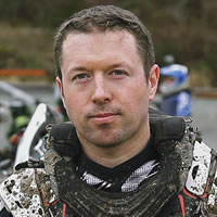 A brown haired man in dirt bike riding gear. 
