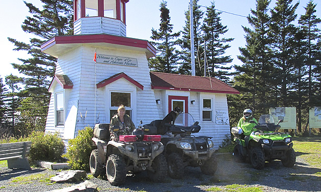 Three ATVs parked at a lighthouse in Nova Scotia. 