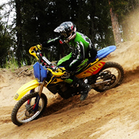 A guy in motocross gear ripping it up on the sand. 