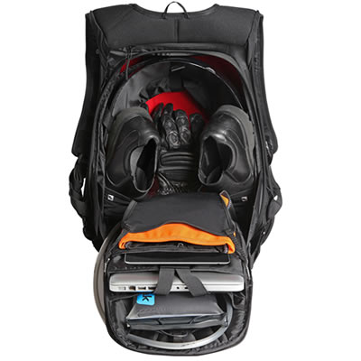 The inside of a black backpack that is open and full with shoes, a laptop and other items. 