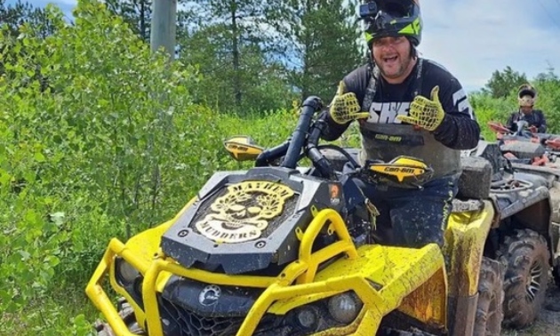 Mike on a yellow ATV giving a thumbs up