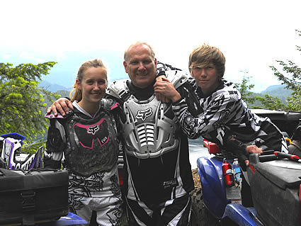 Three people wearing riding gear and smiling