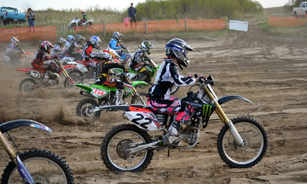 A group of motocrossers taking off from the starting gate. 