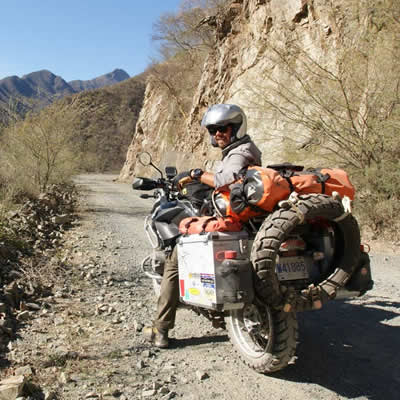 Kevin Chow on his BMW adventure bike, riding down a dirt road through canyons. 