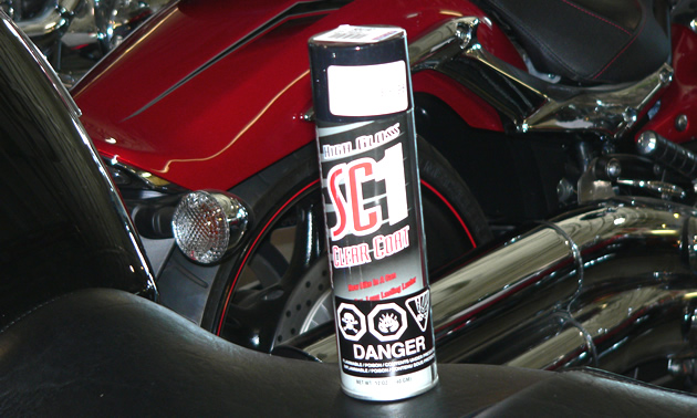 A can of detailing spray sitting on the seat of a motorcycle. 