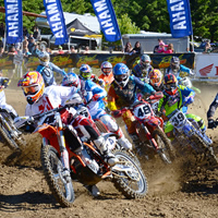 A group of motocross racers coming off the starting line. 