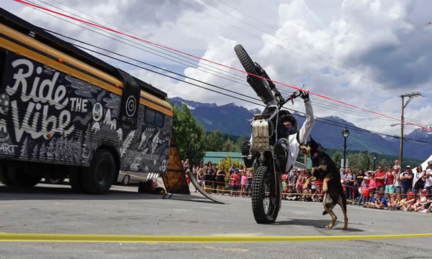 Sam King wheelies with his dog, Tiki, in front of onlookers at a street show. 
