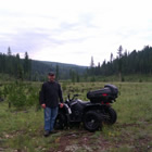 a man standing beside a quad in the backcountry