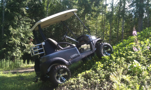 Photo of a tricked-out golf cart climbing a small hill. 