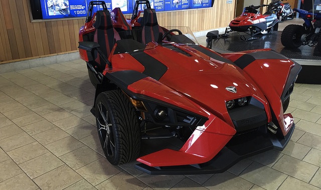 A red Polaris Slingshot sitting in a showroom.