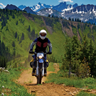 A man riding an off road bike through the mountains. 
