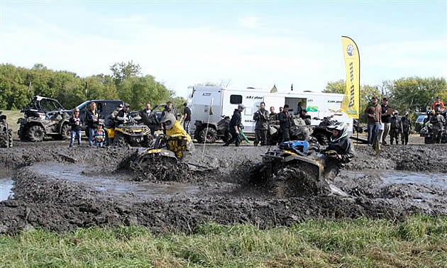 Two ATVers going through a mud bog. 