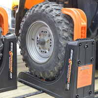 The tire of an ATV secured by clamps on a trailer. 