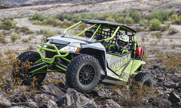 Two men riding in an Arctic Cat Wildcat side by side. 
