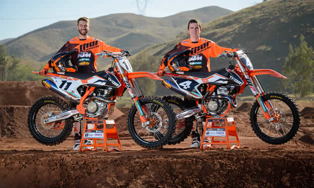 Kaven Benoit and Cole Thompson standing beside their orange KTMs. 