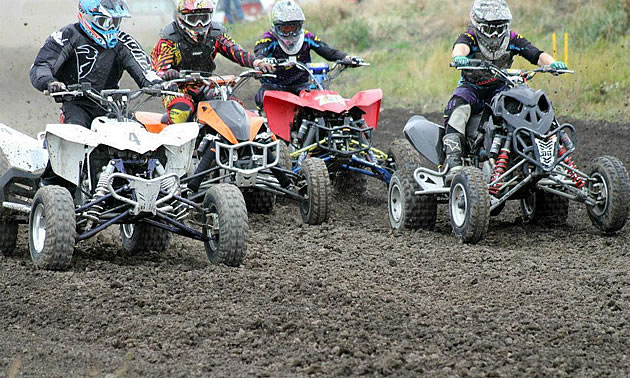 A group of ATVs racers on a dirt track. 