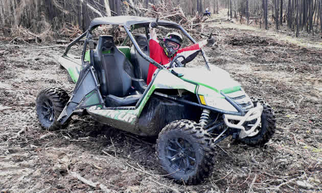 A woman in a red shirt sitting in an Arctic Cat Wildcat Side by side. 