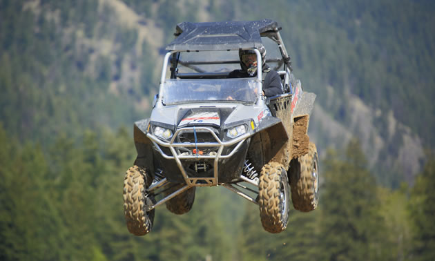 Photo of a guy in a UTV flying through the air. 