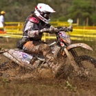 A woman dirt biker riding through mud