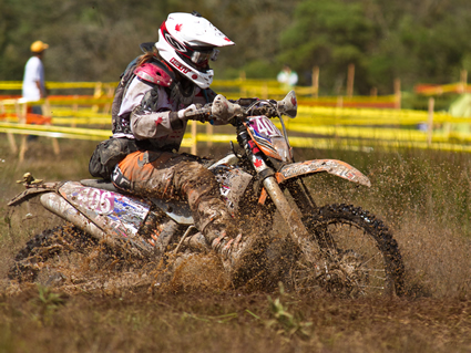 A woman dirt biker riding through mud