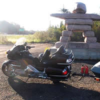 A motorcycle parked by an inukshuk. 