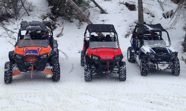 Three sporty looking side by sides lines up in the snow. 