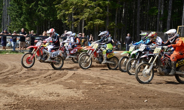 A group of motocrossers coming off the starting line. 